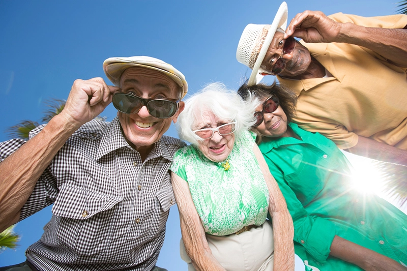 four senior citizens wearing sunglasses looking down at the camera